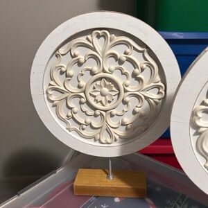 white carved wood medallion on a stand